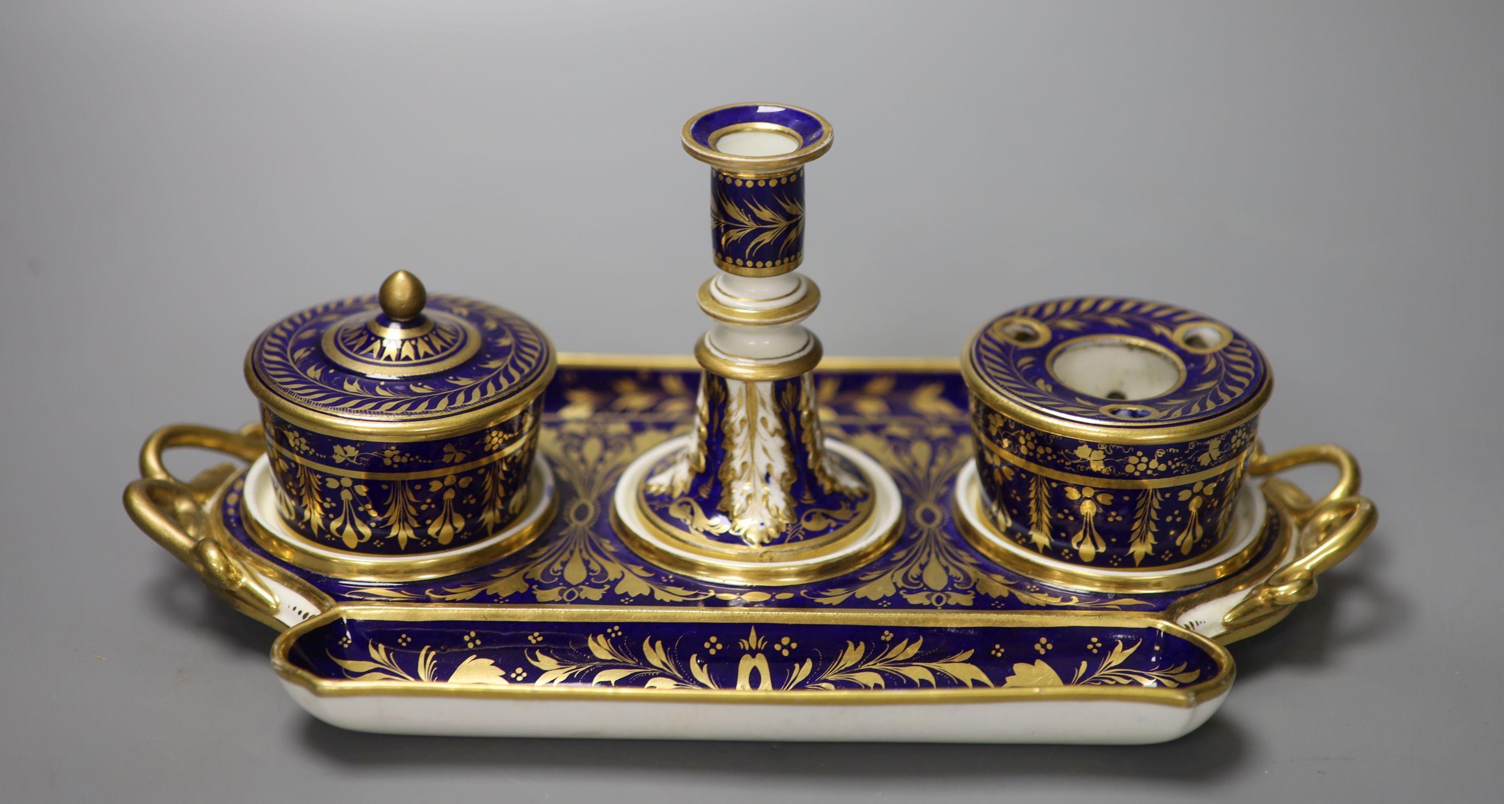 A Derby inkstand ornately gilded on a cobalt blue ground having a sander and cover, inkpot and taper stick, red marks, width 27cm